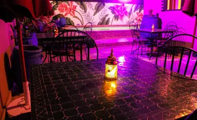 a candle on a table in a room with pink lights at Majorel Pearl Hotel-Riad-Restaurant Piscine&Spa in Marrakech