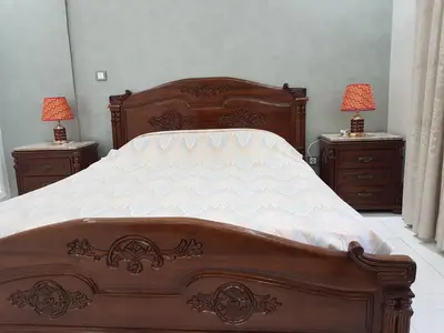 a bedroom with a large wooden bed with two night stands at Appartement warda in Marrakech