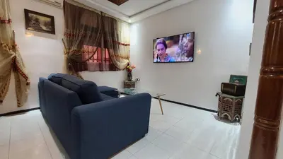 a living room with a couch and a tv on a wall at Appartement warda in Marrakech