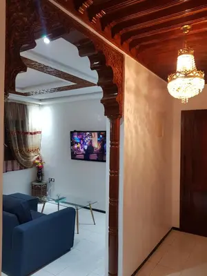 a living room with a blue couch and a chandelier at Appartement warda in Marrakech