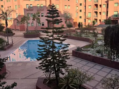 a pine tree in a courtyard next to a swimming pool at Al ATLAS résidence in Marrakech
