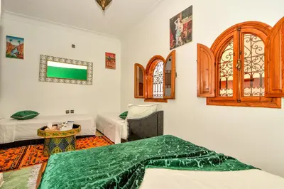 a room with two beds and a tv on the wall at Riad ouhmidi in Marrakech