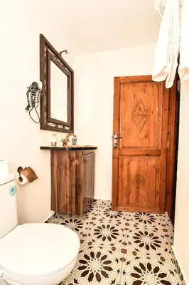 a bathroom with a toilet and a wooden door at Riad ouhmidi in Marrakech