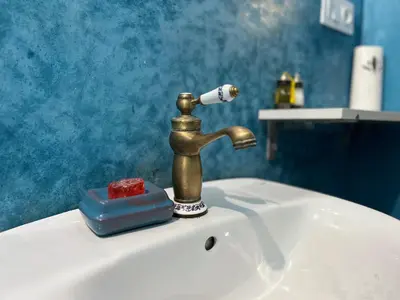 a bathroom sink with a gold faucet and a blue wall at Riad Imndi in Marrakech