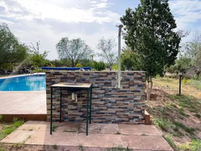 a table next to a brick wall next to a swimming pool at Maison avec piscine et grand jardin 1 hectare in Marrakech