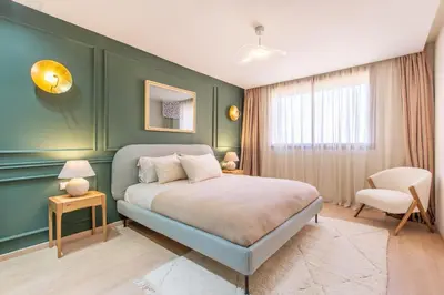 a green bedroom with a bed and a chair at ZARI Boutique ApartHotel in Marrakech