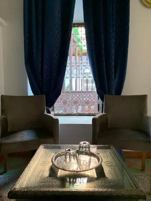 a living room with a table and two chairs and a window at Riad Malida Marrakech in Marrakech