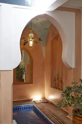 a room with a swimming pool and a chandelier at Riad Al Ibtikar in Marrakech