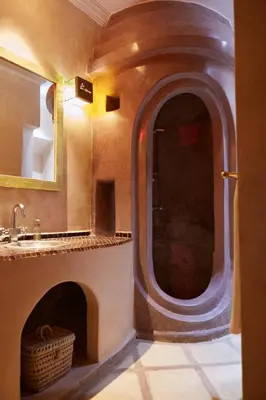 a bathroom with a fireplace with a sink and a mirror at Riad Al Ibtikar in Marrakech