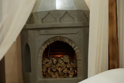 a stone fireplace with a pile of logs in it at Riad Al Ibtikar in Marrakech