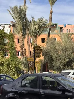 a car parked in a parking lot with palm trees at Riad Naïel 3 piscines in Marrakech