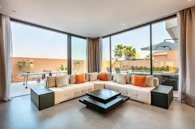 a living room with a couch and large windows at Villa Perle Rouge, Piscine , Cuisinière, Billard, playStation5 in Marrakech