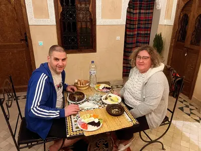 a man and woman sitting at a table with food at Riad La Rose Des Sables in Marrakech