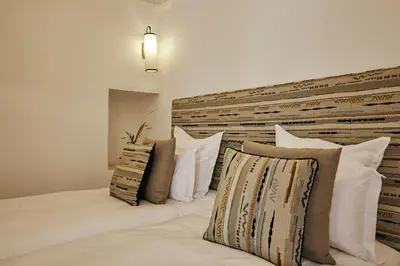 a bed with white pillows and a wooden headboard at Ryad Selyen in Marrakech