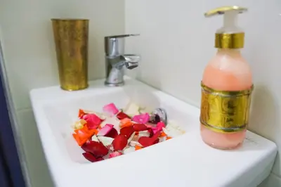 a bathroom sink with a bottle of drink and flowers on it at Winarouze house in Marrakech