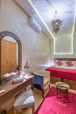 a bedroom with a bed and a desk and a mirror at Palais Tara & Spa in Marrakech
