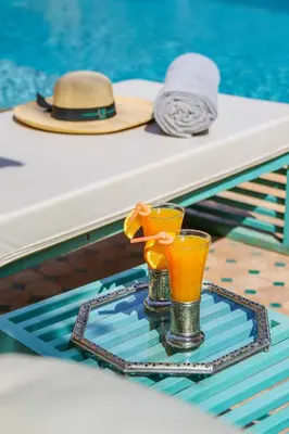 a tray with two glasses and a hat next to a pool at Villa Taj Sofia & Spa in Marrakech