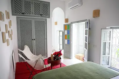a bedroom with a bed and a chair and windows at Riad Amour in Marrakech