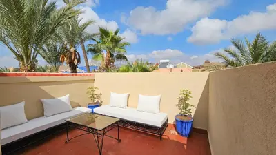 a balcony with a couch and a table and palm trees at Duplex el Madina in Marrakech