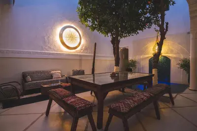 a table and chairs in a living room with a tree at Riad Villa Berna under Swiss Management in Marrakech