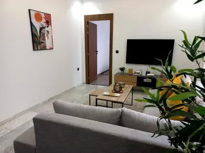 a living room with a couch and a tv at Appartement cosy au cœur de Marrakech avec piscine in Marrakech