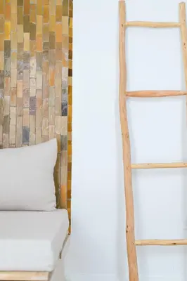 a wooden shelf next to a bed with a pillow at Riad Rahal in Marrakech