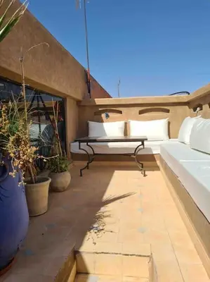 a balcony with white beds and potted plants at Le Havre de paix in Marrakech