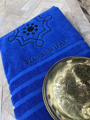 a blue napkin with a silver plate on top at Riad Al Wifak in Marrakech