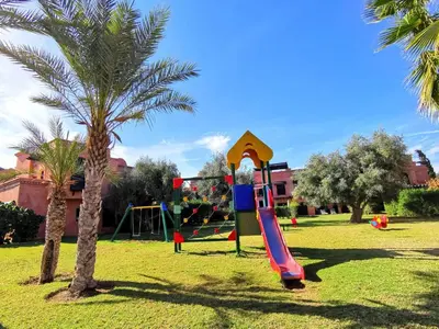a playground with a slide in a park with a palm tree at Appart atlas resort in Marrakech