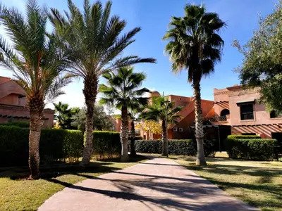 a sidewalk with palm trees in front of a building at Appart atlas resort in Marrakech