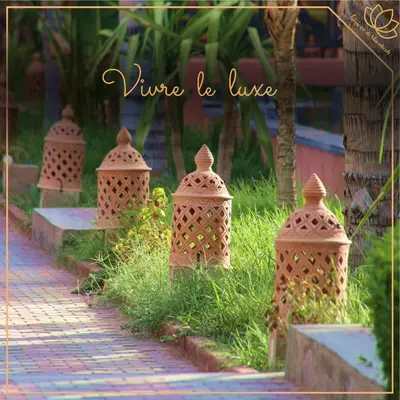a row of vases in the grass next to a sidewalk at Palmera de Marrakech in Marrakech