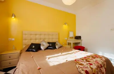 a bedroom with a large bed and a yellow wall at résidence qarya syahia private roof terrasse in Marrakech
