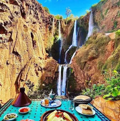 a table with plates of food in front of a waterfall at résidence qarya syahia private roof terrasse in Marrakech