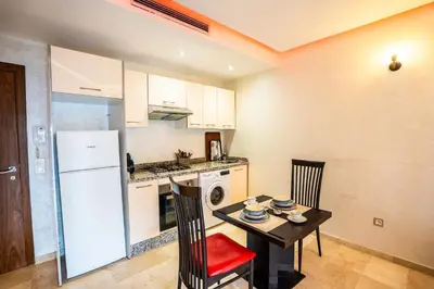 a kitchen with a table and a white refrigerator at Apartment pool marrakech in Marrakech