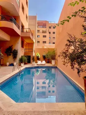 a swimming pool in front of a building at Cosy appartement au cœur de Gueliz in Marrakech