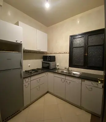a kitchen with white cabinets and a sink and a microwave at JHDARINNA in Marrakech