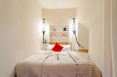 a bedroom with a white bed with a red pillow at Riad Dar Zitouna Marrakesh - entire house in exclusivity in Marrakech