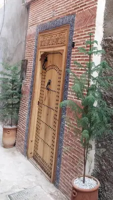 a brick building with a wooden door with a tree in front at Riad dar Karam in Marrakech