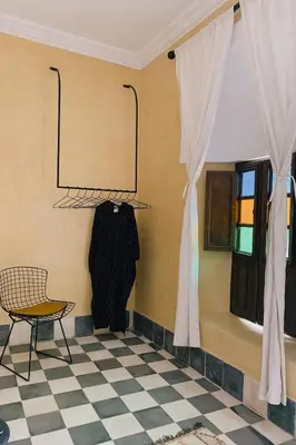 a room with a chair and a coat hanging on a wall at Riad Maison 24 in Marrakech
