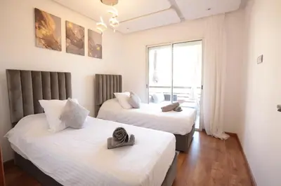 two beds in a room with a window at APPARTEMENT RIAD WHITE GOLDEN in Marrakech