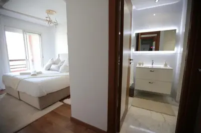 a white bedroom with a bed and a sink at APPARTEMENT RIAD WHITE GOLDEN in Marrakech