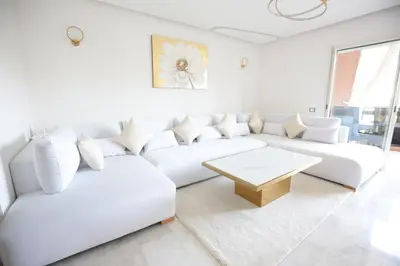 a white living room with a white couch and a table at APPARTEMENT RIAD WHITE GOLDEN in Marrakech