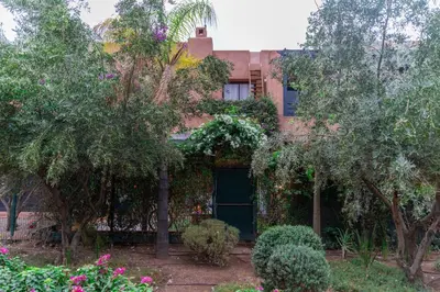 a building with a green door in the middle of trees at Pavillon Affaoui Golf & Waky in Marrakech