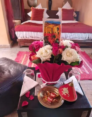 a table with flowers on it with two beds at Maison ALPHEA SPA HAMMAM in Marrakech
