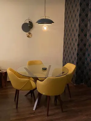 a dining room with a glass table and yellow chairs at Appartment Zaina in Marrakech