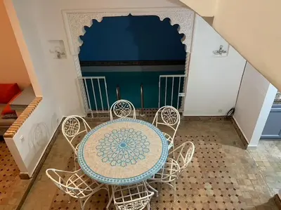 a table and chairs in a room with a wall at Ryad de charme authentique piscine calme in Marrakech