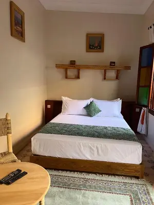 a bedroom with a bed and a table and a chair at Riad Dar Les Freres in Marrakech