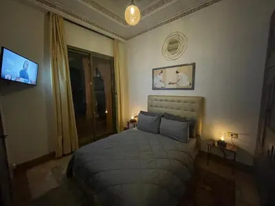 a bedroom with a bed in a room with a tv at Au Cœur de la Palmeraie de Marrakech in Marrakech