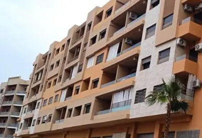 a tall building with a palm tree in front of it at Luxury apartment Gueliz (2 min walk from Train Station) in Marrakech
