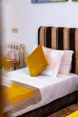 a bed with yellow and white pillows on it at Riad Nalan & Spa in Marrakech